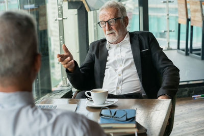 Mid adult man with coffee and woman sitting on table