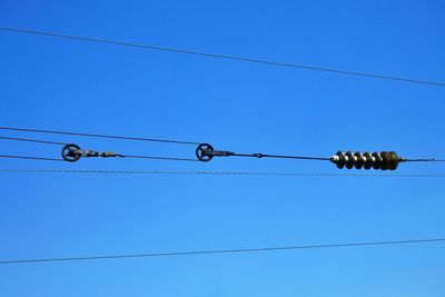 Low angle view of power lines against clear blue sky