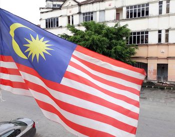 Close-up of malaysia flag against buildings in city