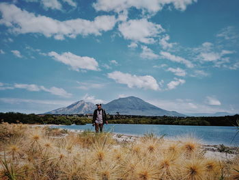 Man walking at lake shore against sky