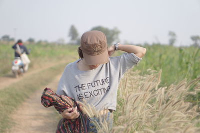 Woman in cap standing on field at farm