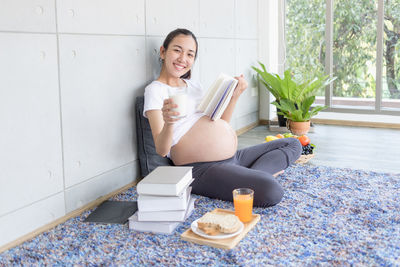 Young woman smiling while sitting against wall