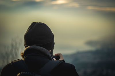 Rear view of man wearing warm clothing against sky at sunset