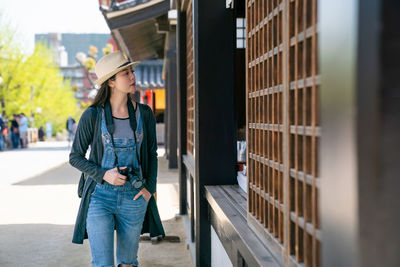 Woman looking away while walking by house