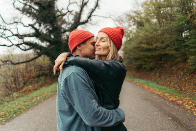 A young man hugs and kisses his girlfriend outside. relationships of modern lovers.