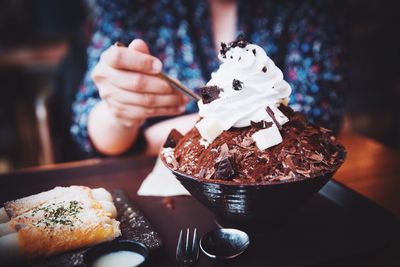 Midsection of woman eating dessert at cafe