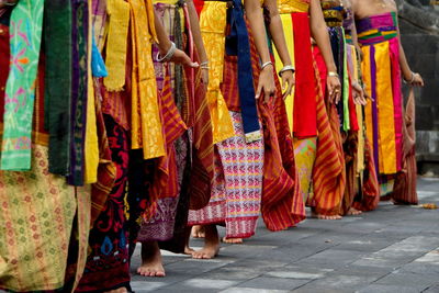 Low section of woman dancing on street with traditional textiles from bali, indonesia.