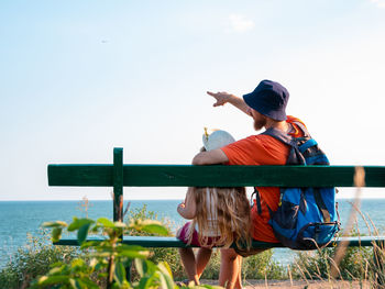 Happy father daughter on wooden bench marine landscape. dad child having fun together. family travel