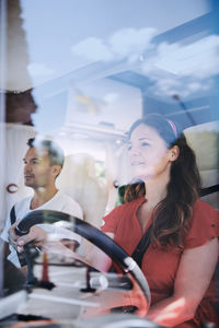 Woman driving van while sitting with man seen through windshield