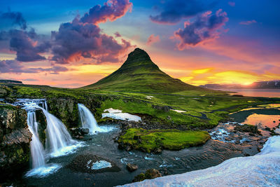 Scenic view of waterfall against sky during sunset