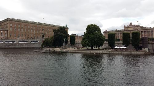 Buildings by river against sky in city