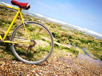 Bicycle wheel on beach against sky