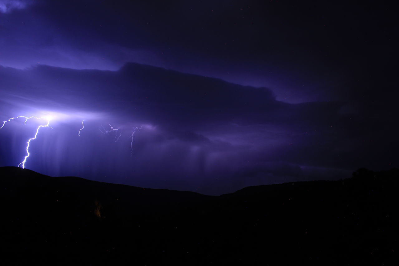 lightning, power in nature, thunderstorm, storm, cloud, beauty in nature, night, thunder, sky, environment, warning sign, dramatic sky, storm cloud, forked lightning, communication, sign, nature, scenics - nature, mountain, no people, darkness, electricity, purple, dark, outdoors, silhouette, illuminated, landscape, awe, light - natural phenomenon, atmospheric mood