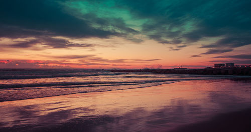 Scenic view of sea against dramatic sky during sunset