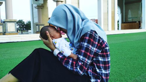 Close-up of mother holding baby while sitting on land