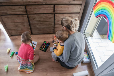 Mother and children painting a rainbow on the window