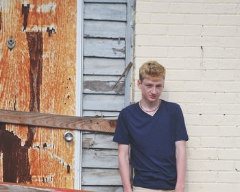 Portrait of teenage boy standing against wall