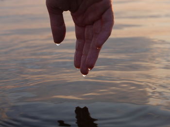 Close-up of droplets falling from hand on the water