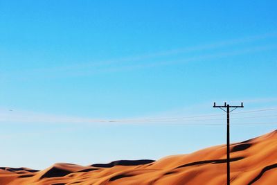 Low angle view of power lines against clear blue sky