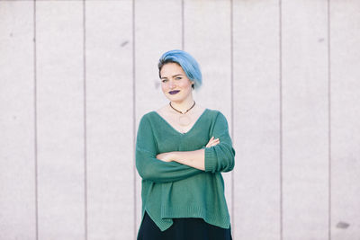 Portrait of a smiling young woman standing against wall