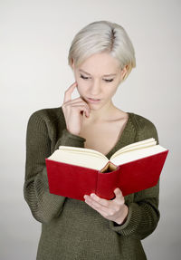 Young woman holding book against white background