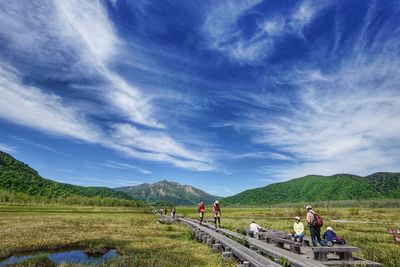 People on road by mountains against sky