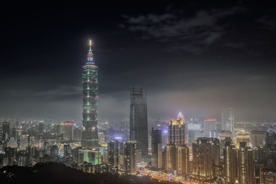 Illuminated buildings in city against sky at night