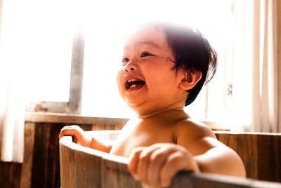 Close-up of happy shirtless boy in bathtub