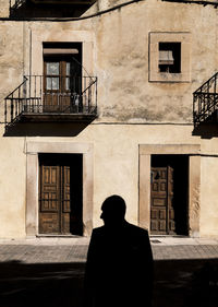 Silhouette of adult man in front of facade of an old building in sepulveda, spain