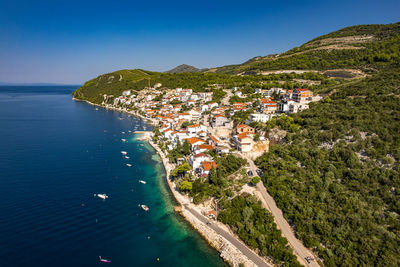 High angle view of townscape by sea against clear sky