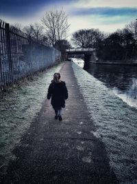 Rear view of siblings walking on road during winter