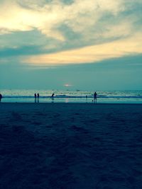 Silhouette people on beach against sky during sunset