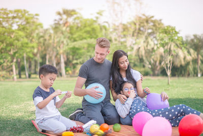 Family enjoying while resting on picnic blanket at park