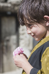 Portrait of boy holding red flower