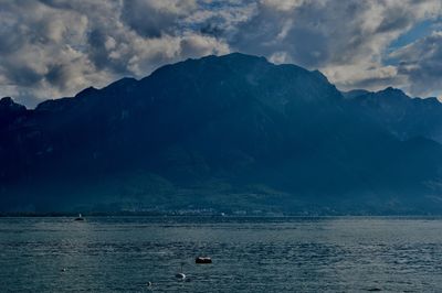 Scenic view of sea by mountains against sky