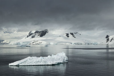 Cloud covered mountains and icebergs in antarctica.