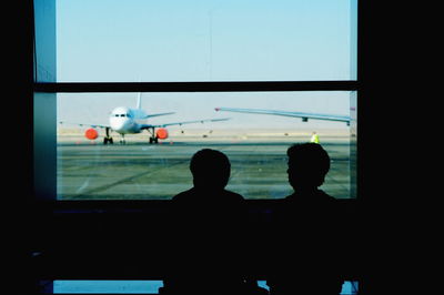 Silhouette people looking at airplane window