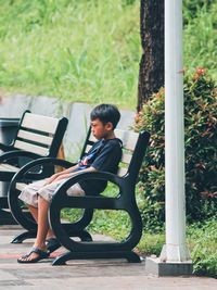 A boy is sitting alone and sad on a park bench.