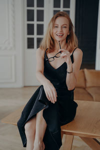 Portrait of young woman sitting on sofa at home