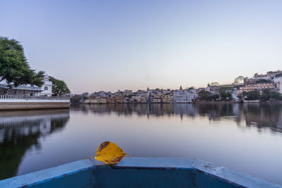 Scenic view of river by buildings against clear blue sky