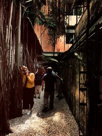 Rear view of people walking on alley amidst buildings in city