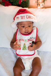 Portrait of cute baby boy sitting on bed at home