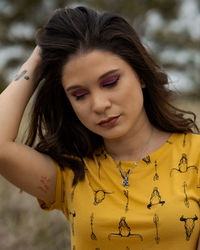 Close-up of beautiful woman with hand in hair standing outdoors