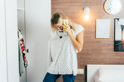 Woman standing against wall at home