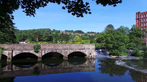 Arch bridge over river against sky