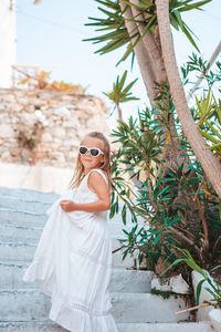 Woman wearing sunglasses standing by tree