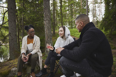 Friends drinking wine in forest