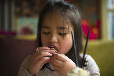 Close-up of girl eating cupcake at home