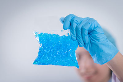 Close-up of scientist holding chemical over white background