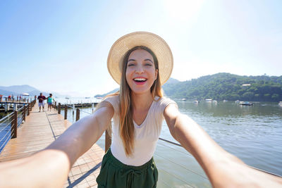 Portrait of young woman wearing hat against sea